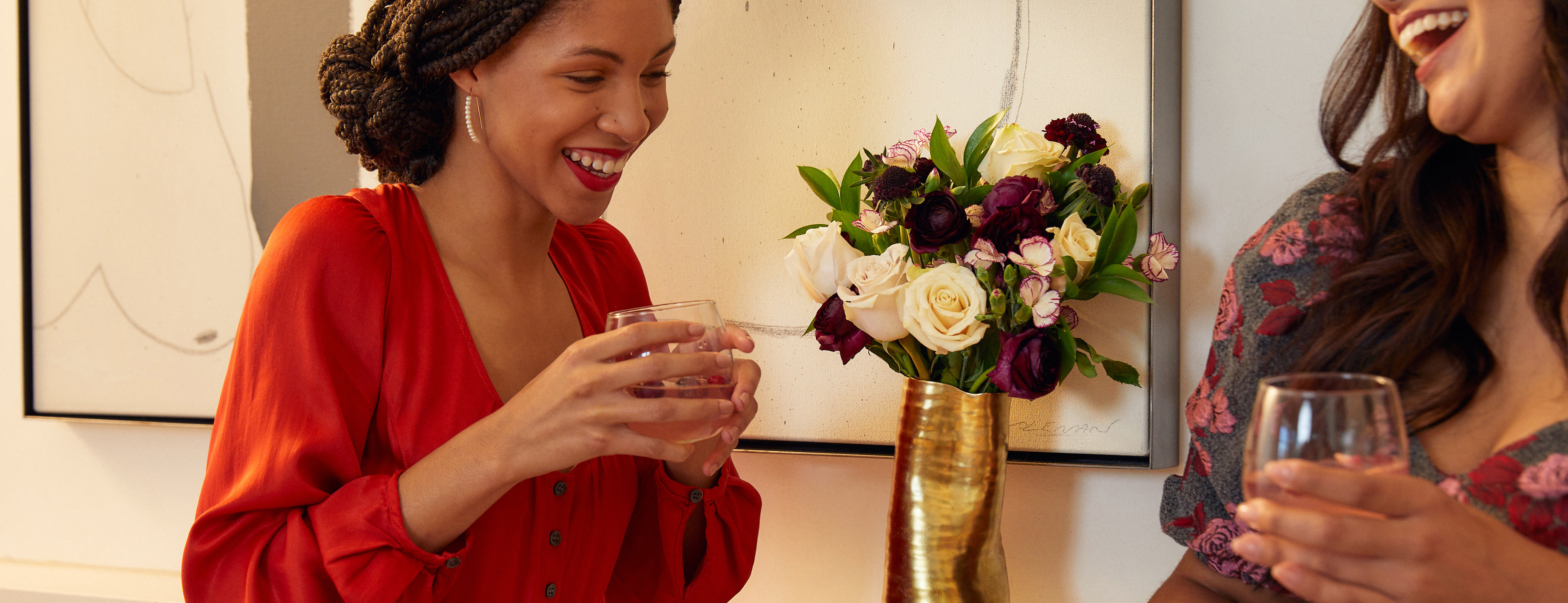 Women celebrating the holidays with a holiday bouquet in a gold vase
